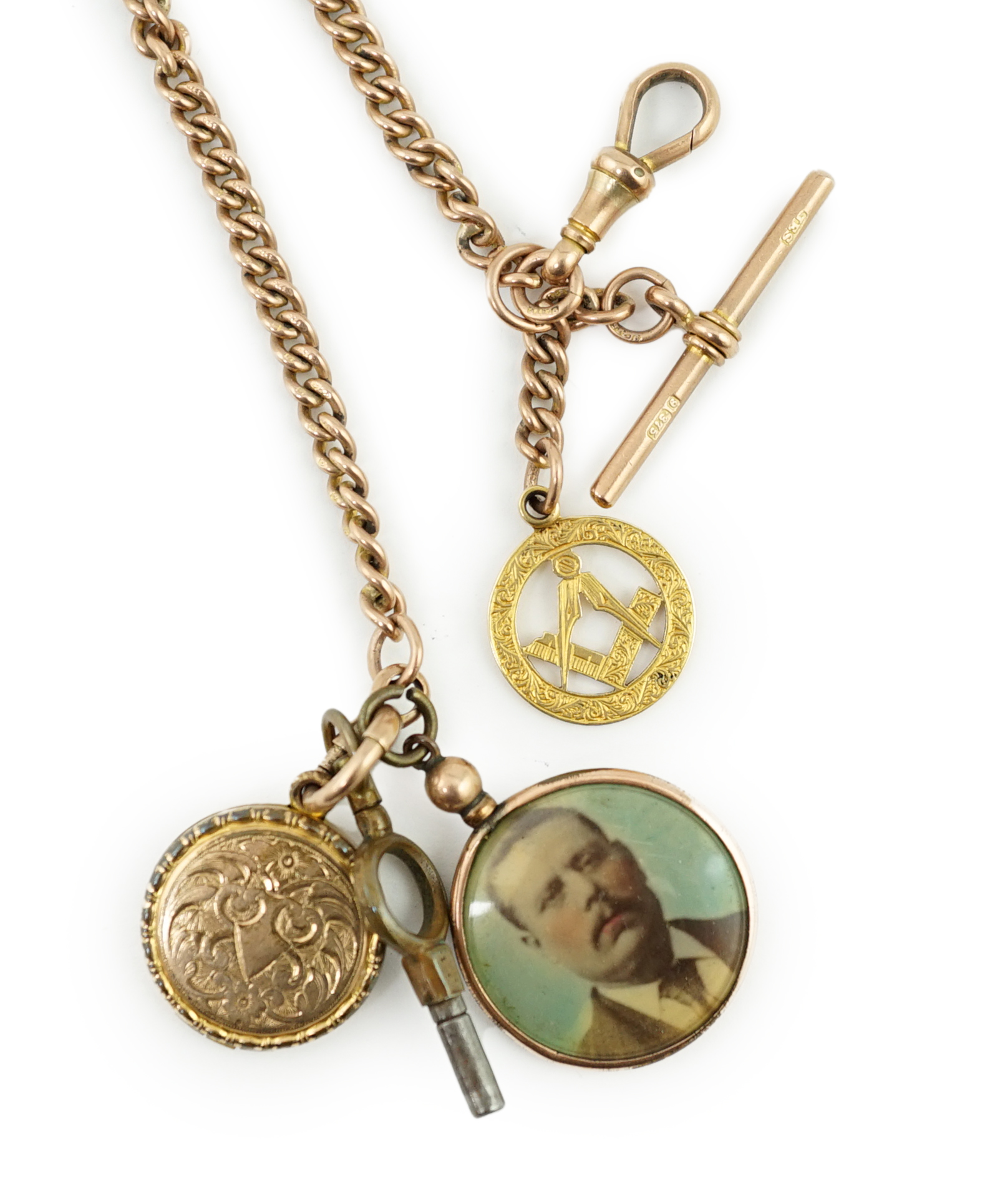 An Edwardian 9ct gold curb link albert, hung with a 9ct gold Masonic charm, locket and a double sided portrait pendant